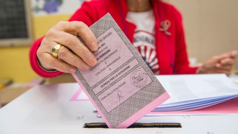 ผู้หญิงคนหนึ่งวางบัตรลงคะแนนของเธอในกล่องลงคะแนนในขณะที่ชาวอิตาลีลงคะแนนเลือกรัฐสภาใหม่ในวันที่ 25 กันยายน 2022 ในเมืองโบโลญญาประเทศอิตาลี