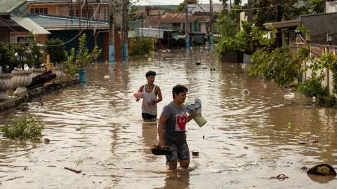 Residents wade through waist-deep flood waters after Typhoon Noru in San Miguel, Bulacan province, the Philippines, on September 26.