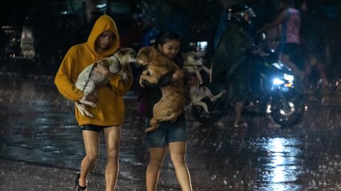 9월 25일 필리핀 마닐라 교외 마리키나시티에서 폭우가 내리는 가운데 주민들이 애완동물을 데리고 대피소로 가고 있다.