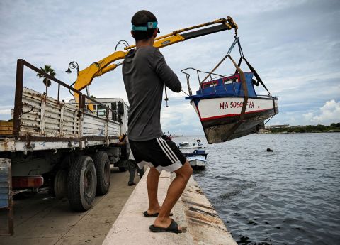 Un uomo aiuta a tirare fuori piccole barche dalla baia dell'Avana a Cuba.