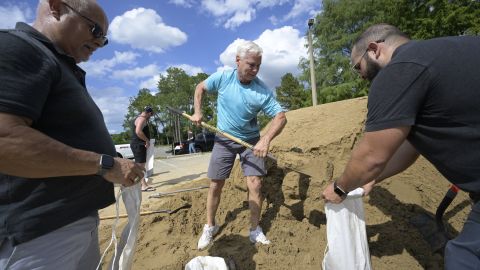 Bob Copeland, center, helps fill free sand bags for Wilbur Villamarin, left, and his son Fabian Villamarin at an Orange County park in preparation for the arrival of Hurricane Ian, on September 26, 2022.