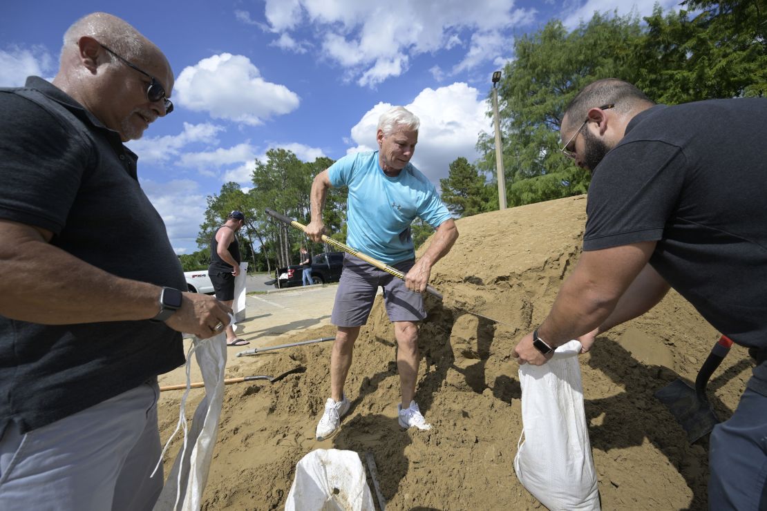 Bob Copeland, center, helps fill free sand bags for Wilbur Villamarin, left, and his son Fabian Villamarin at an Orange County park in preparation for the arrival of Hurricane Ian, on September 26, 2022.