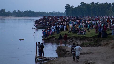 People gather along the riverbank after a boat capsized near the town of Boda on September 25, 2022.