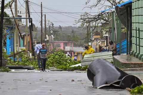 People clean debris from a street in Consolacion del Sur, Cuba, on Tuesday after Hurricane Ian made landfall.