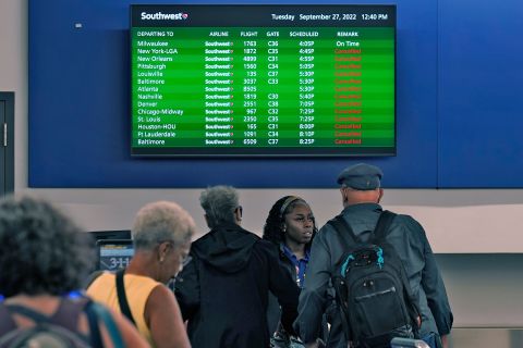 Southwest Airlines passengers check in near a sign that shows canceled flights at the Tampa International Airport on Tuesday.