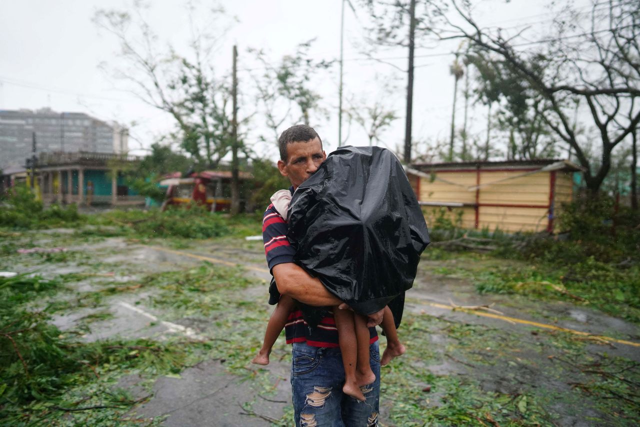 A man carries his children thru rain and debris in Pinar del Rio on Tuesday.
