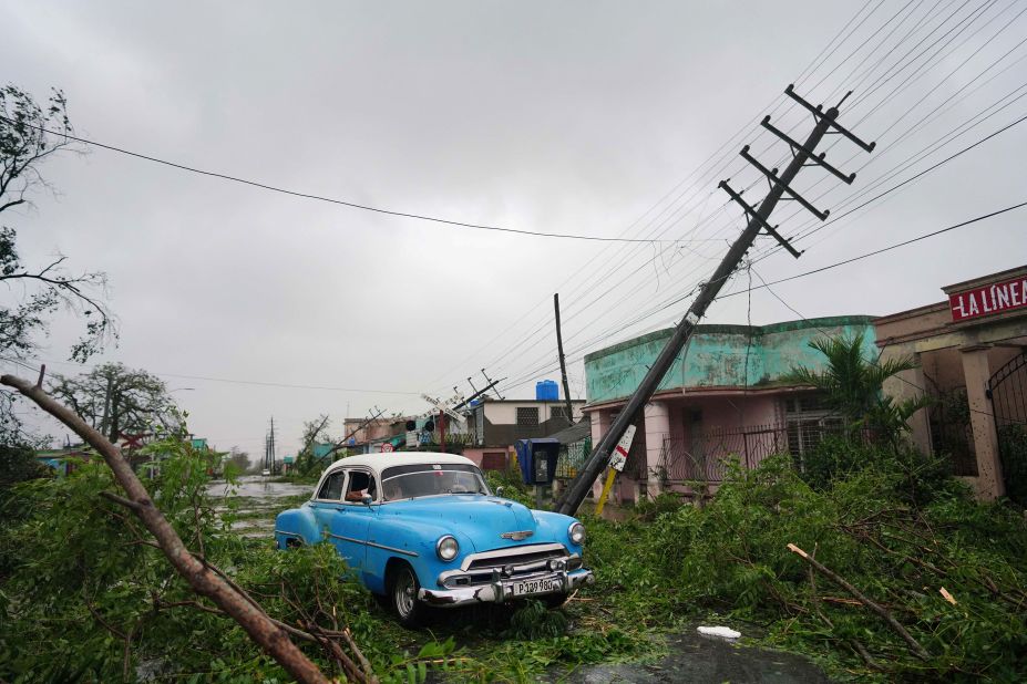 People drive through debris in Pinar del Rio on Tuesday.