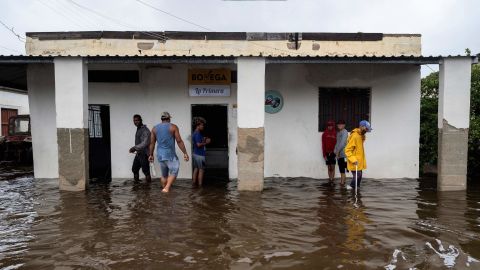 People stand outside a flooded warehouse in Batabano, Cuba, on September 27, during the passage of Hurricane Ian.