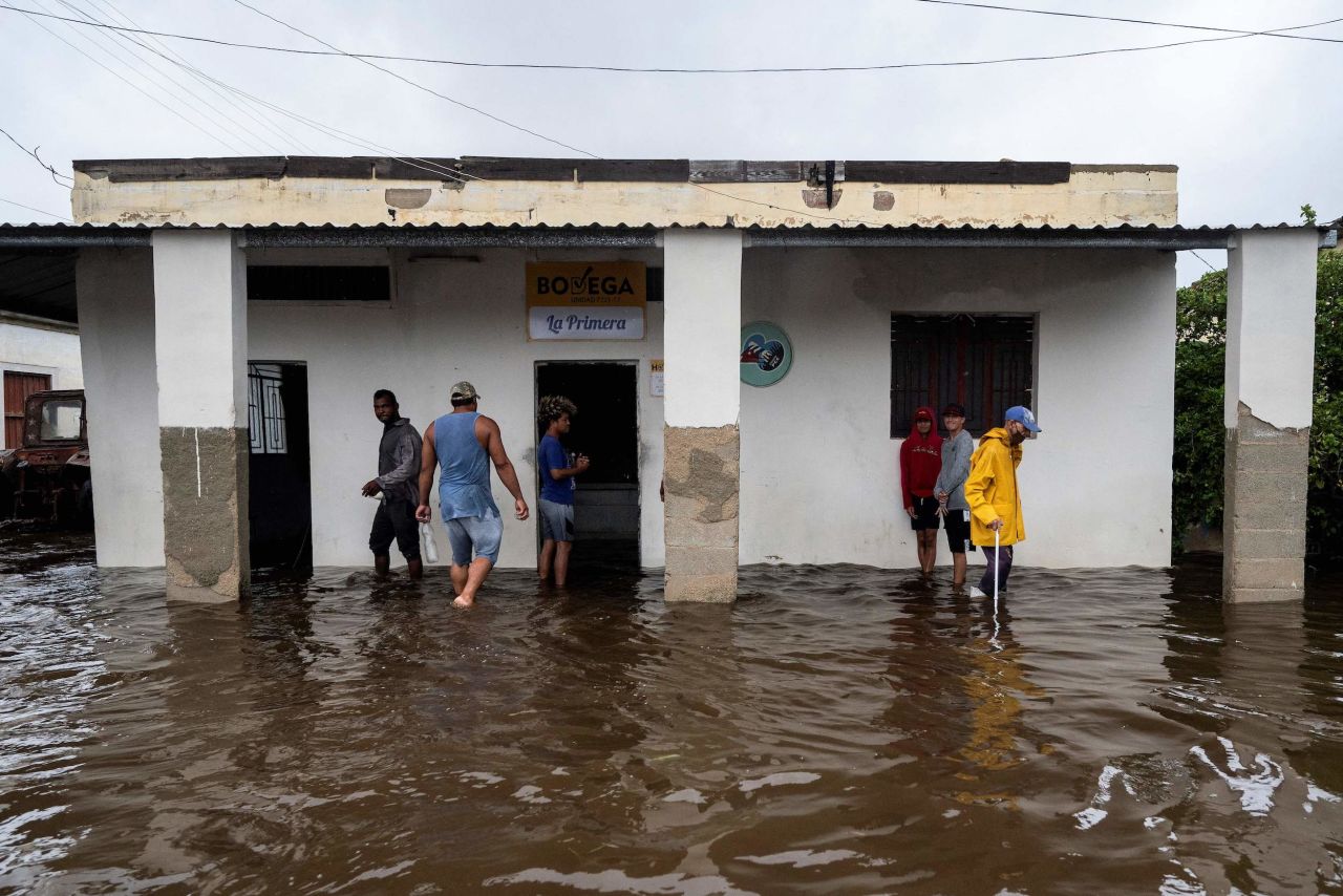 People stand outside a flooded warehouse in Batabano on Tuesday.