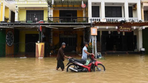 People push motorbikes on a flooded road in Hoi An city, Quang Nam province on September 28, 2022.