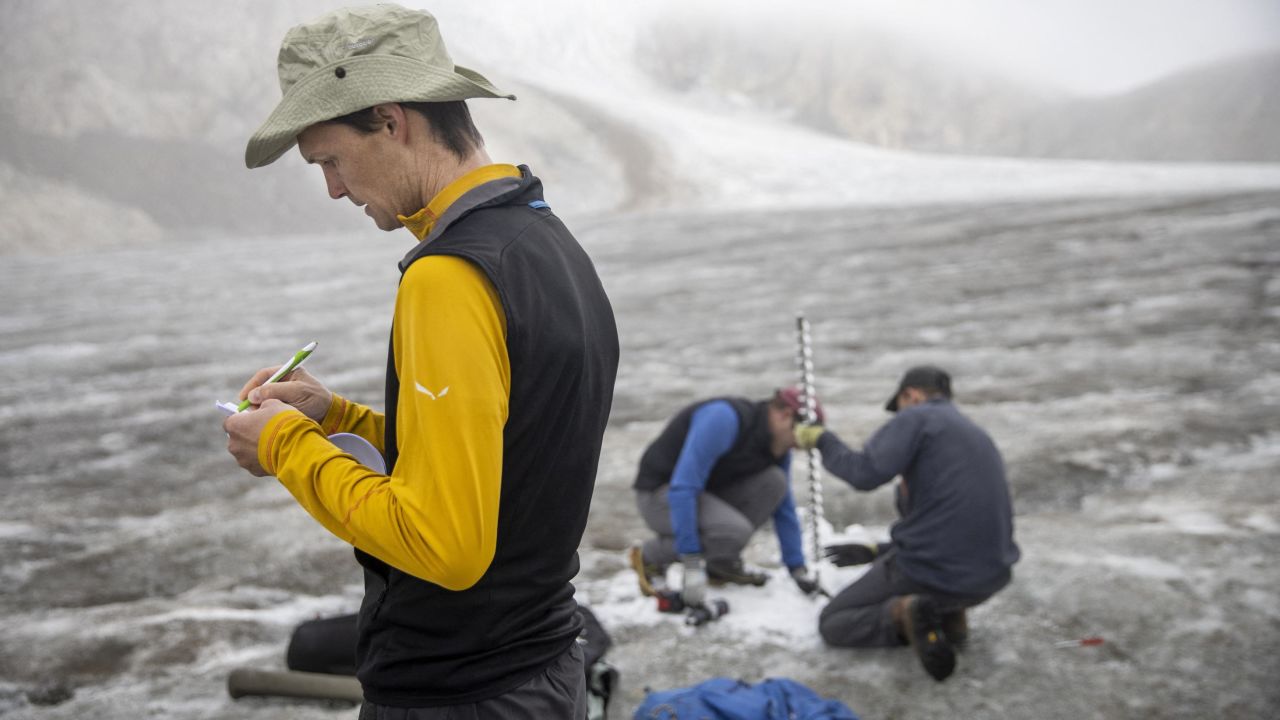 Glaciologist Matthias Huss, front, takes note of the decrease of ice while other members of the GLAMOS team drill a new hole in the Gries glacier.