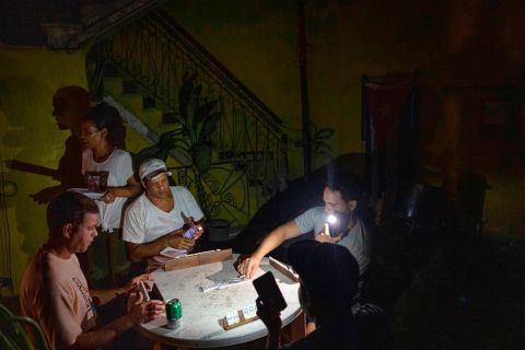 People play dominoes by flashlight during a blackout in Havana, Cuba, on Wednesday. Crews in Cuba are working to restore power for millions Wednesday after the storm battered the western region with high winds and dangerous storm surge, <a href=