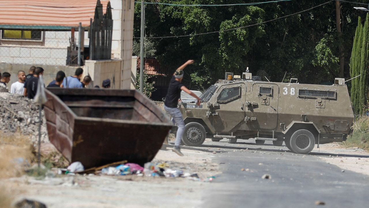 A Palestinian hurls a stone at an Israeli army vehicle during clashes in Jenin on September 28.