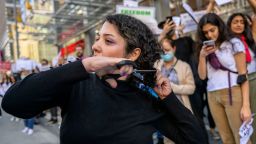 An activist cuts her hair in protest over the death of Mahsa Amini outside The New York Times building in New York City on Tuesday.