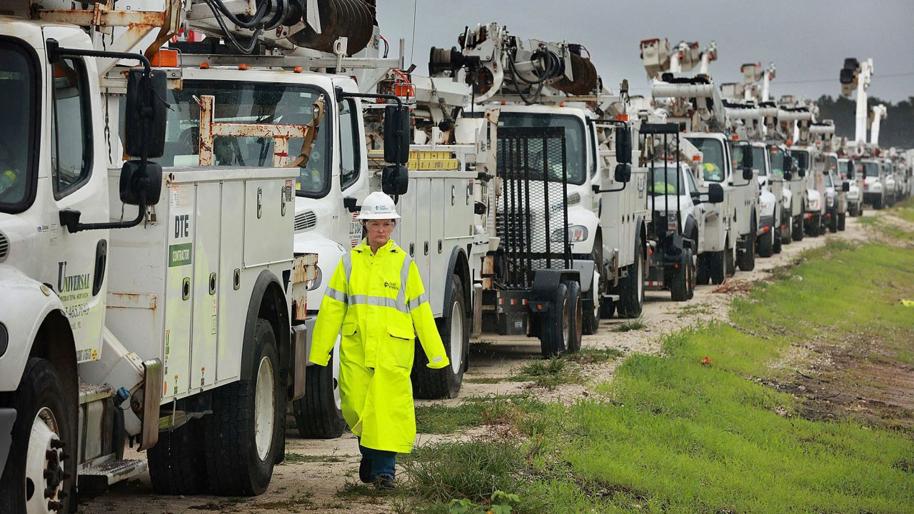 Heather Danenhower, with Duke Energy, walks around utility trucks that are staged in a rural lot in The Villages of Sumter County on Wednesday.