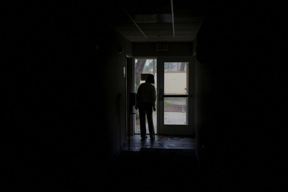 A woman surveys damage through a door during a power outage in Fort Myers on Wednesday.