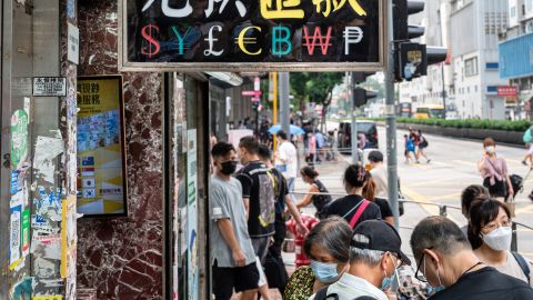 Pedestrians walk past a currency money exchange shop in Hong Kong.