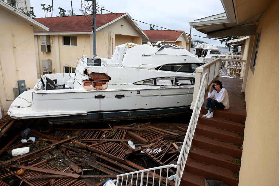 Brenda Brennan sits next to a boat that pushed up against her apartment building in Fort Myers on Thursday. She said the boat floated in around 7 p.m. Wednesday.