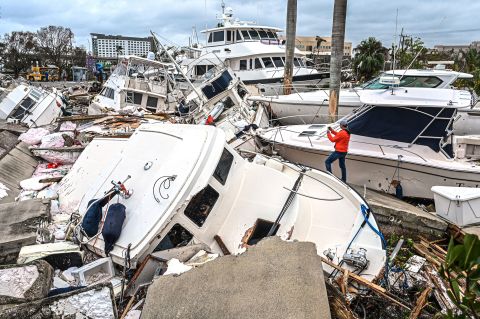 A man takes photos Thursday, September 29, of boats that were damaged by Hurricane Ian in Fort Myers, Florida.