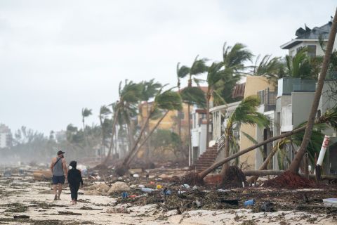 People walk along the beach looking at property damaged in Bonita Springs, Florida, on Thursday.