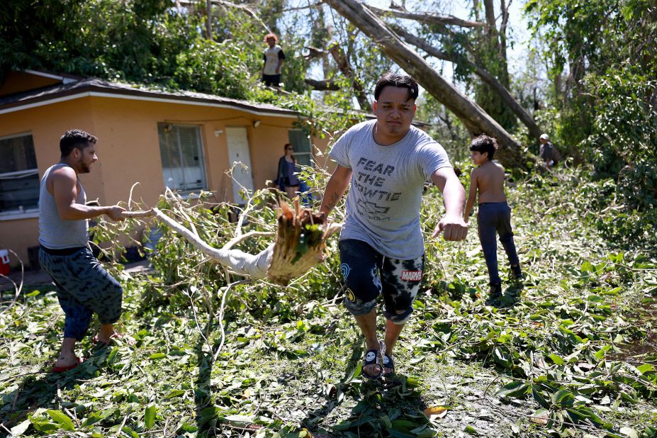 People clear a large tree off their home in Fort Myers on Thursday.