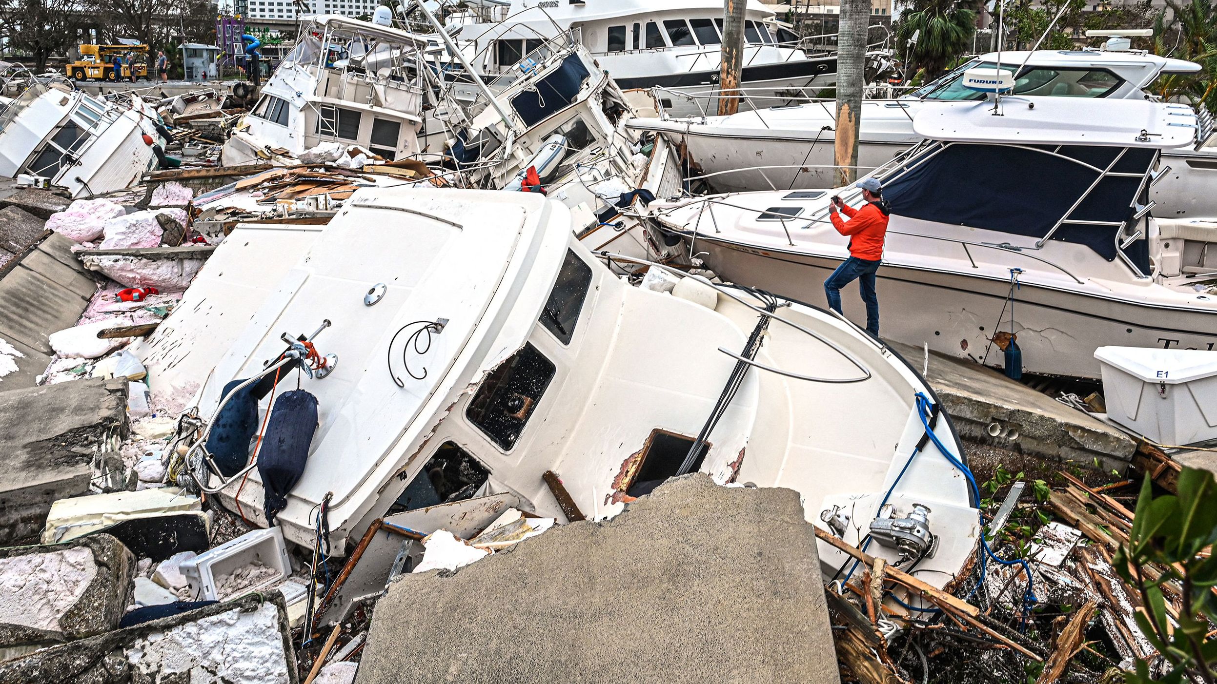 A man takes photos Thursday, September 29, of boats that were damaged by Hurricane Ian in Fort Myers, Florida.