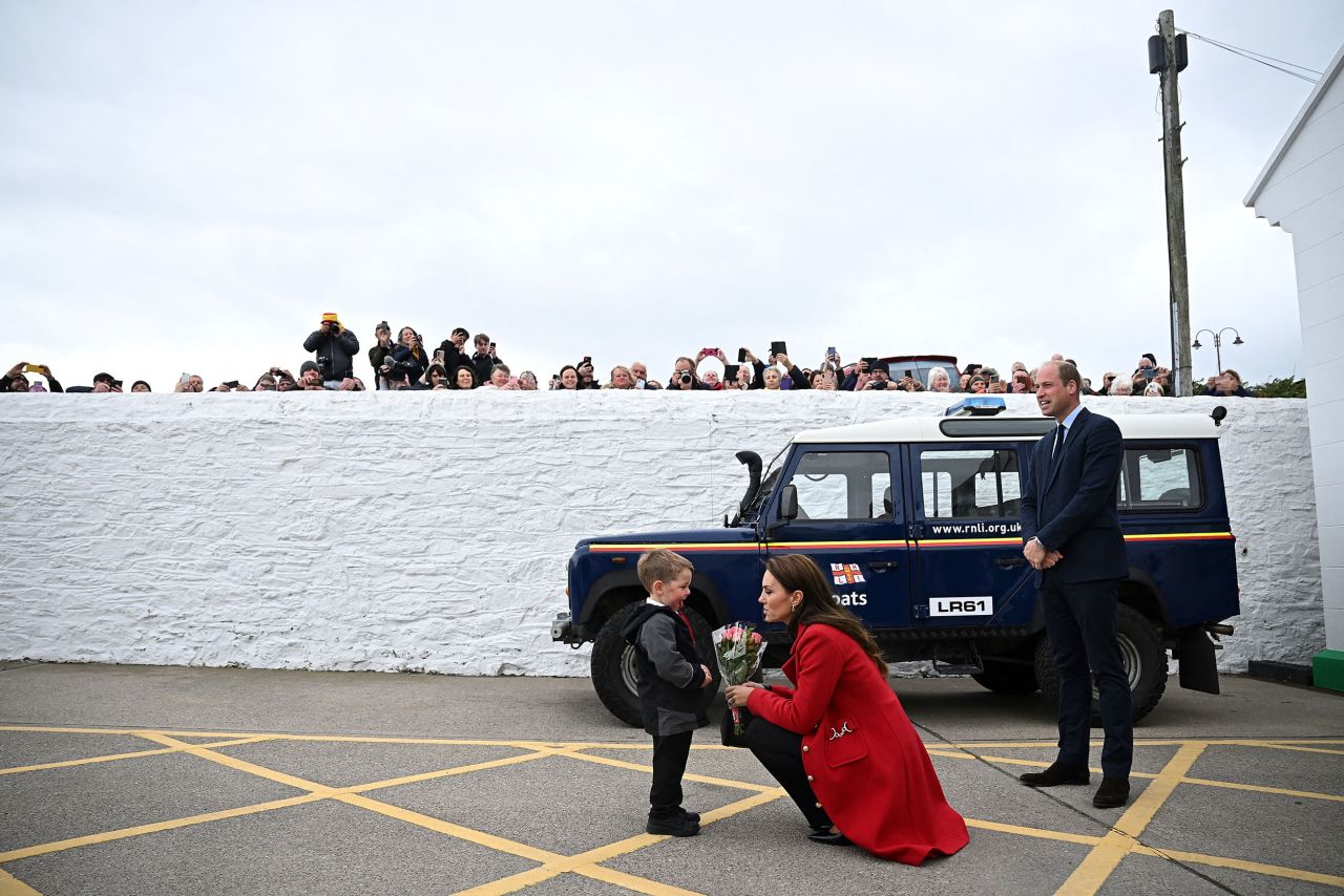 Britain's Prince William watches as his wife Catherine, the Princess of Wales, is presented with flowers by 4-year-old Theo Crompton during their visit to a lifeboat station in Anglesey, Wales, on Tuesday, September 27.