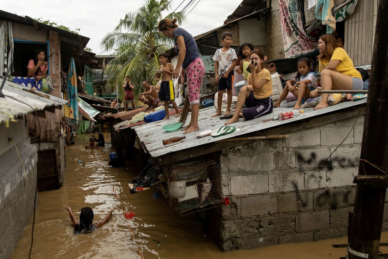 People look out from the roofs of their homes as they wait for flooding to subside in San Miguel, Philippines, on Monday, September 26. <a href="https://www.cnn.com/2022/09/26/asia/typhoon-karding-noru-philippines-deaths-intl-hnk/index.html" target="_blank">Typhoon Noru</a> made landfall the day before.