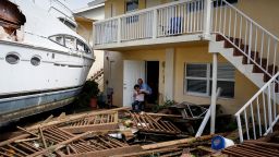 A man helps a woman next to a damaged boat amid a downtown condominium after Hurricane Ian caused widespread destruction, in Fort Myers, Florida, U.S., September 29, 2022.