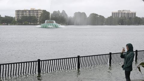 A woman stands above a flooded walkway surrounding Lake Eola on Thursday in the aftermath of Hurricane Ian.