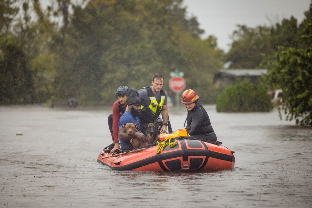 A resident of Orange County, Florida, and a couple of dogs are rescued from floodwaters on Thursday.