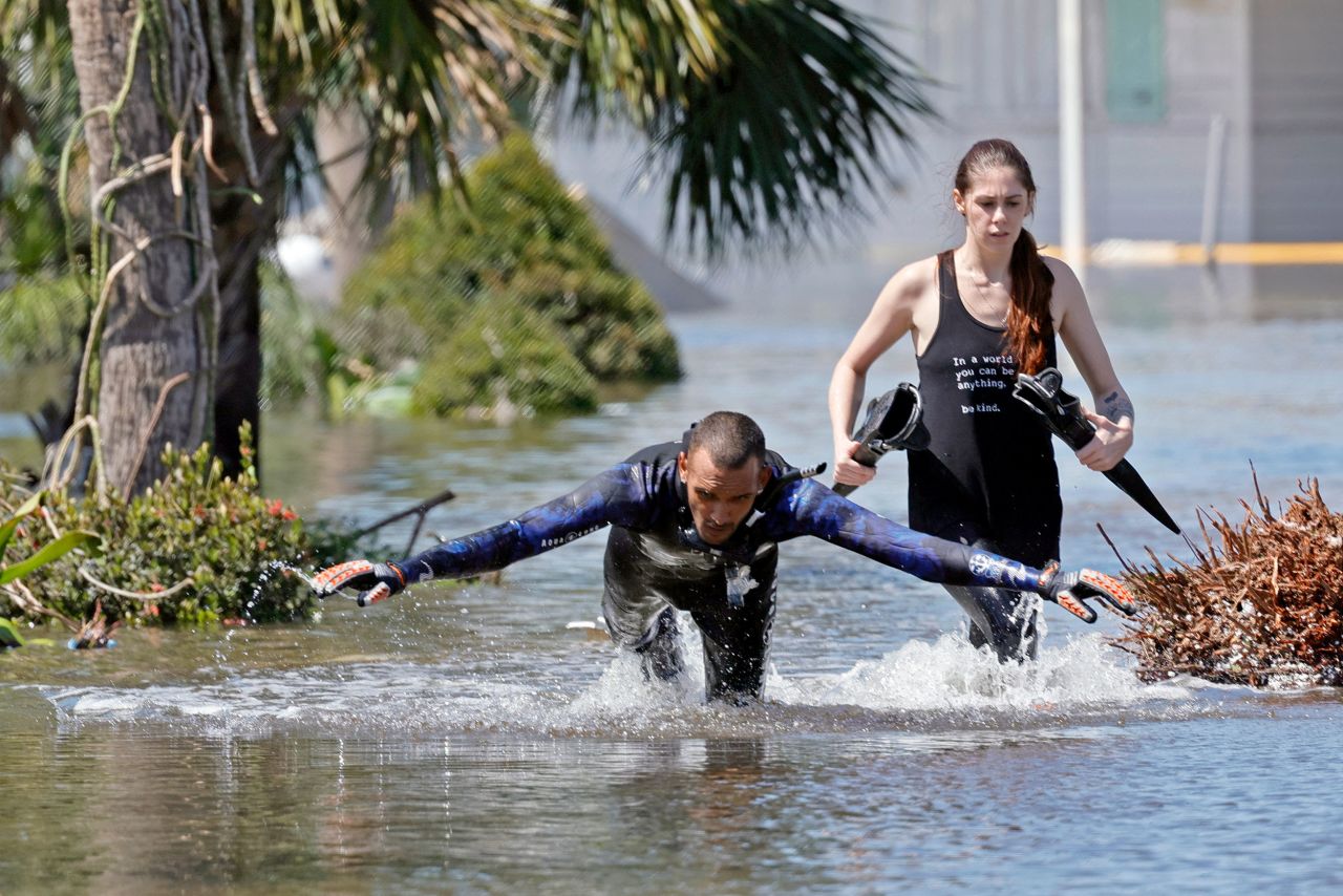 Jonathan Strong dives into floodwaters while he and his girlfriend, Kylie Dodd, knock on doors to help people in a flooded mobile home community in Iona, Florida, on Thursday. "I can't just sit around while my house is intact and let other people suffer," he said. "It's what we do: community helping community."