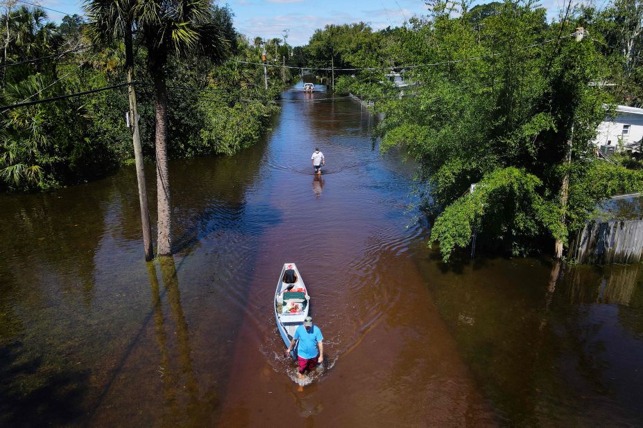 A man tows a canoe through a flooded street of his neighborhood in New Smyrna Beach, Florida, on Friday.
