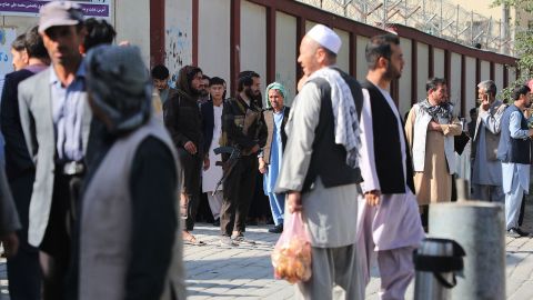 Taliban fighters stand guard as people search for relatives outside a hospital in Kabul on September 30, following a blast at a learning center in the Afghan capital.