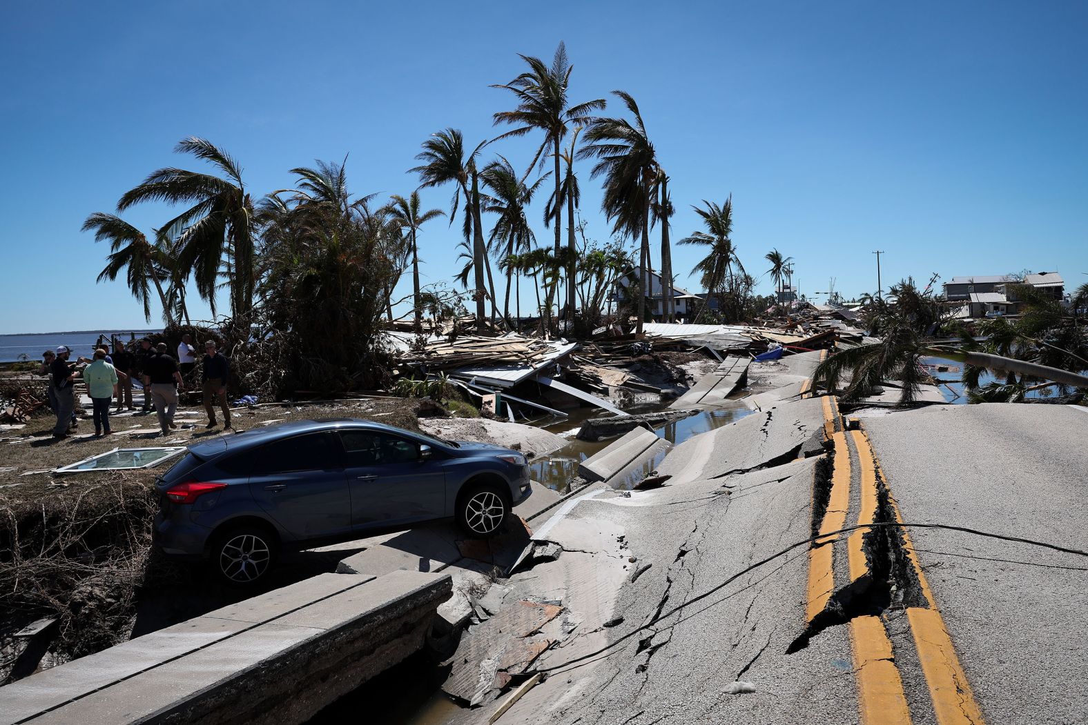 The wreckage of a car teeters on a buckled roadway on Friday in Matlacha, Florida.