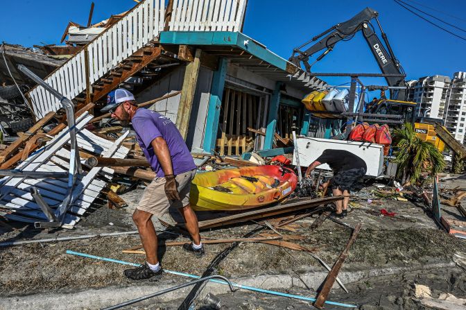 Workers and residents clear debris from a destroyed bar in Fort Myers on Saturday, October 1.