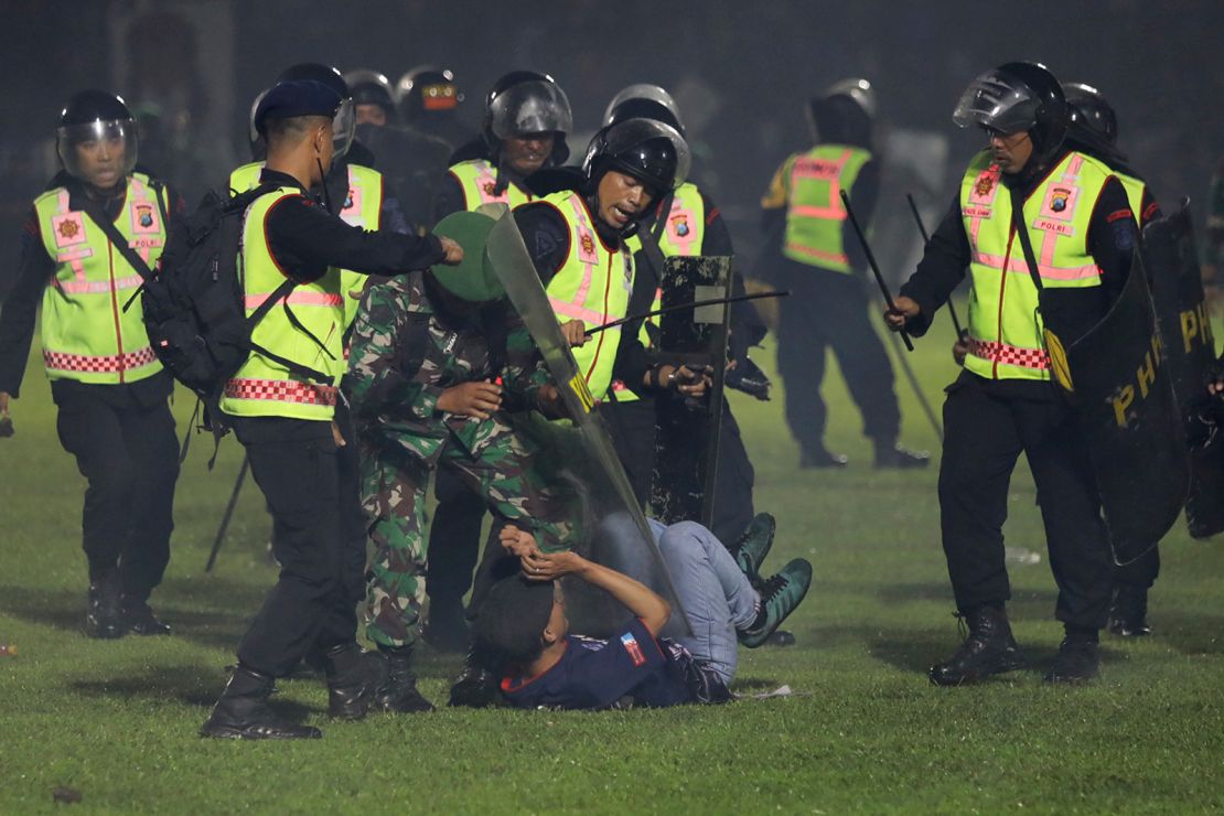 Indonesian security officers detain a fan on the pitch.