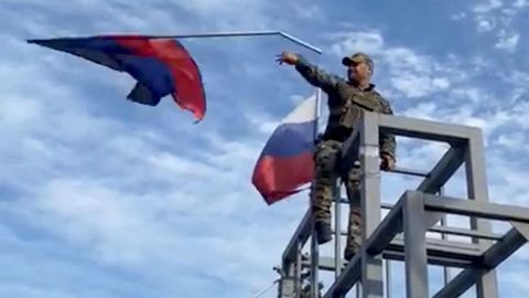 A member of the Ukrainian troop brings down a Donetsk Republic flag hoisted on a monument in Lyman, Ukraine in this screen grab obtained from social media video released on October 1, 2022.