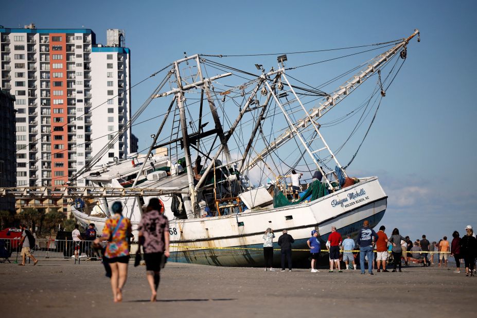 Beachgoers look at a large shrimping boat that was swept ashore in Myrtle Beach, South Carolina, on Saturday.