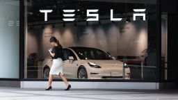 A woman walks past the front window of a Tesla Store in Shinjuku, Japan on June 24, 2022. 