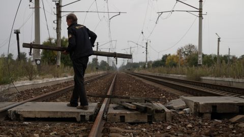 A local man carries firewood gathered from the ruins across the railway that splits Lyman in two on October 2, 2022.