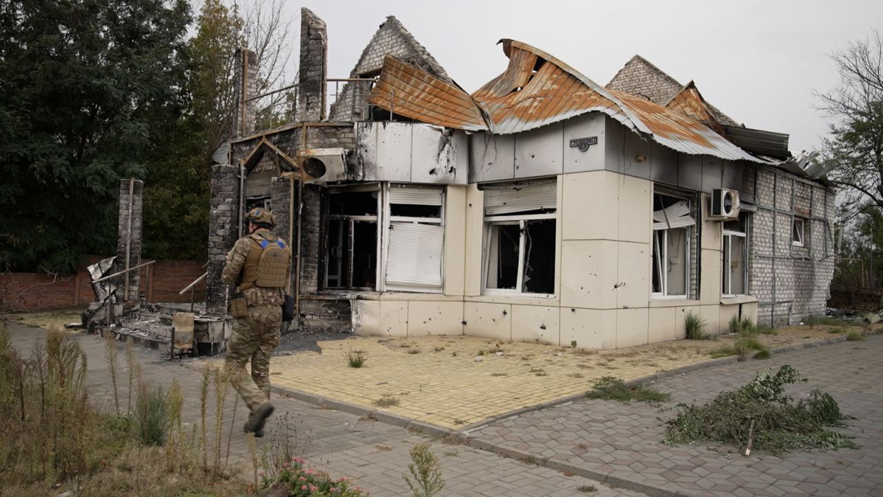 A Ukrainian soldier with the Dnipro-1 unit walks past a damaged building in central Lyman, Ukraine, on Sunday, October 2, 2022.