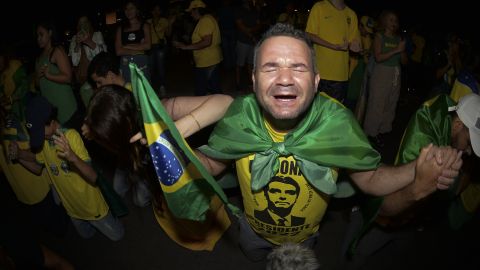Supporters of Brazilian President Jair Bolsonaro pray as they listen to partial results after polls in Brasilia's general election on October 2, 2022. 