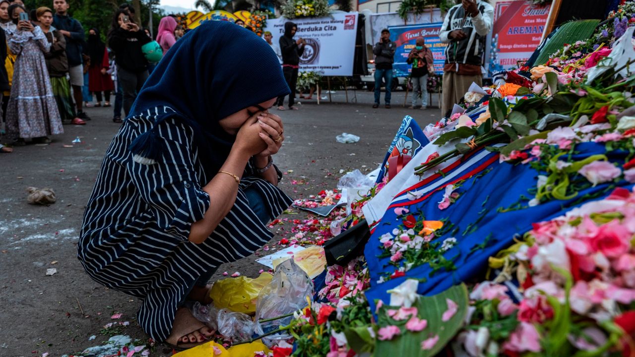 A woman prays by flowers left to remember the victims outside Kanjuruhan Stadium on October 3, 2022 in Malang, Indonesia.
