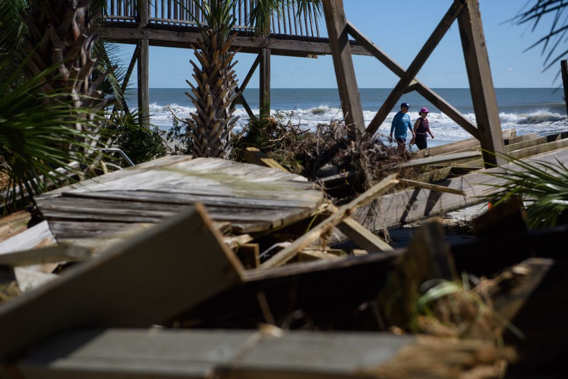 A couple walks past damage from Hurricane Ian on Litchfield Beach, South Carolina on October 1, 2022.  