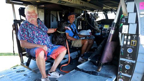एक आदमी अपने कुत्ते के साथ फ्लोरिडा के पाइन आइलैंड में फ्लोरिडा आर्मी नेशनल गार्ड हेलीकॉप्टर में निकालने की तैयारी करता है।