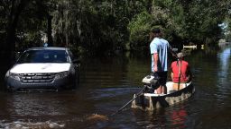 Two men motor a boat past a stranded car to pick up items from a home that was flooded by rain from Hurricane Ian on October 1, 2022 in Orlando, Florida. The storm caused widespread flooding in several areas of Orlando after making landfall in the Fort Myers area as a Category 4 hurricane. 