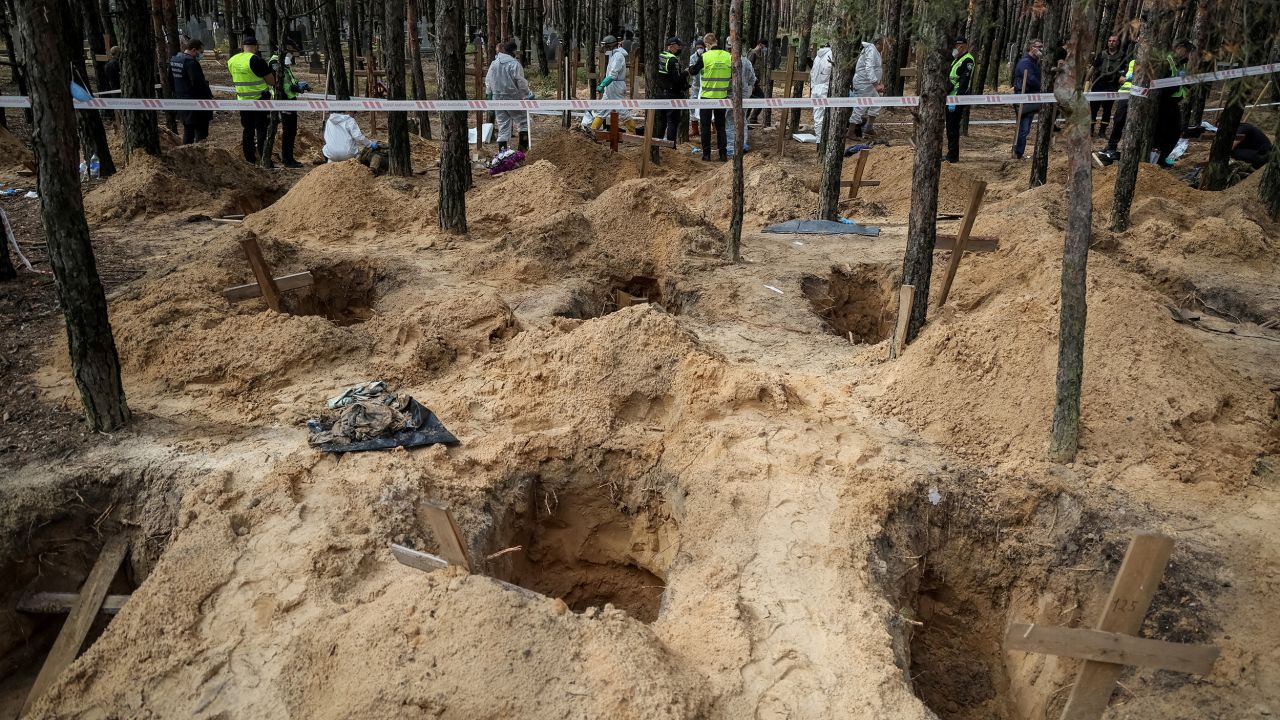 Police and experts work at a mass burial site during an exhumation, in the town of Izium, recently liberated by Ukrainian forces.