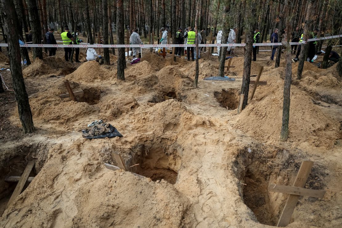 Police and experts work at a mass burial site during an exhumation, in the town of Izium, recently liberated by Ukrainian forces.     