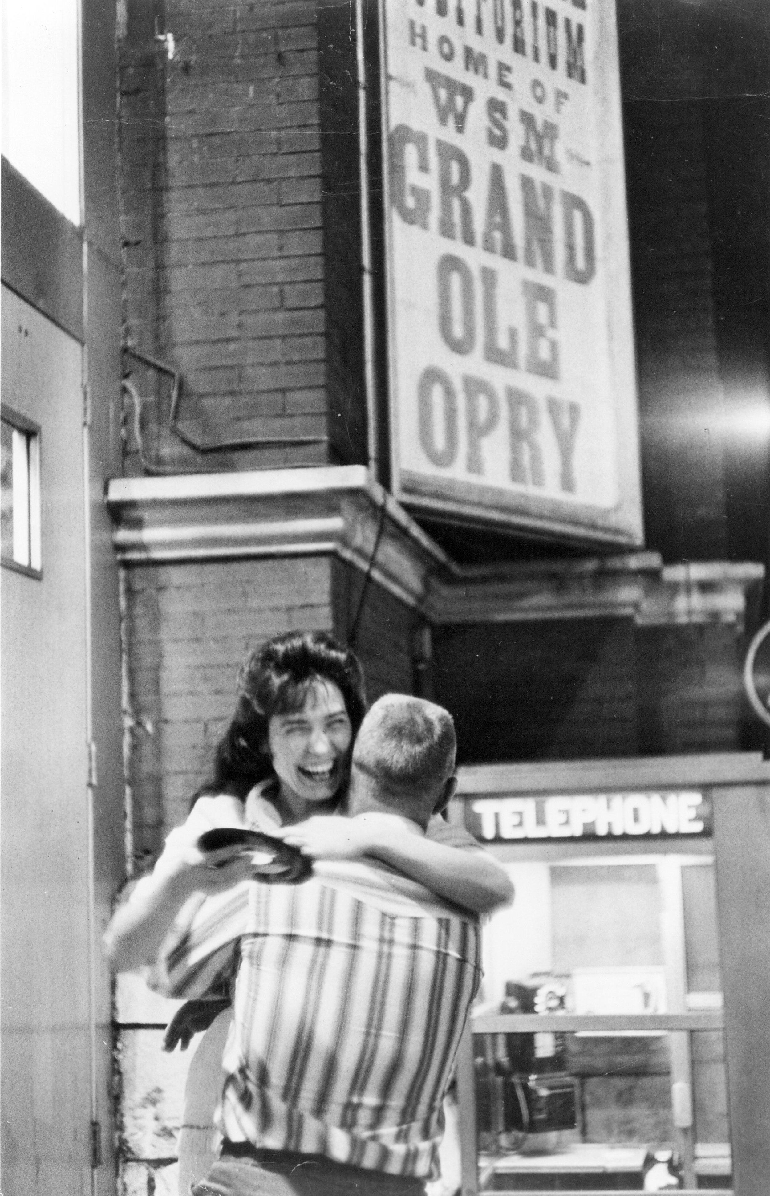 Lynn hugs a man while holding a record outside the Grand Ole Opry in Nashville, Tennessee, circa 1960.